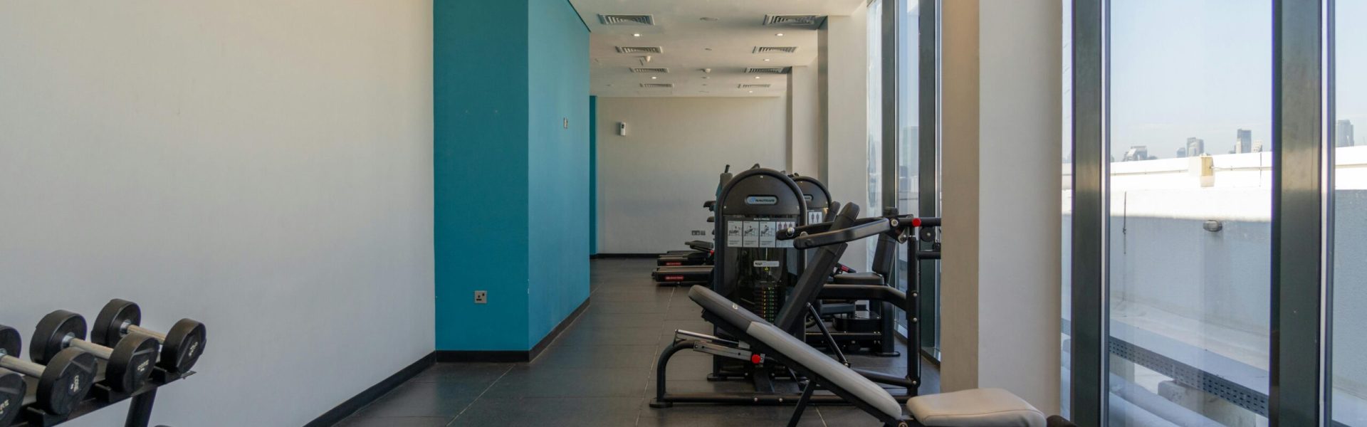 Spacious gym with exercise machines and dumbbells, perfect for bodybuilding and fitness enthusiasts.