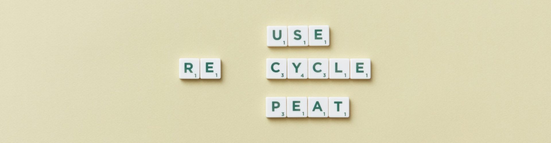 Letter tiles spelling 'reuse recycle repeat' on a simple background, promoting sustainability.
